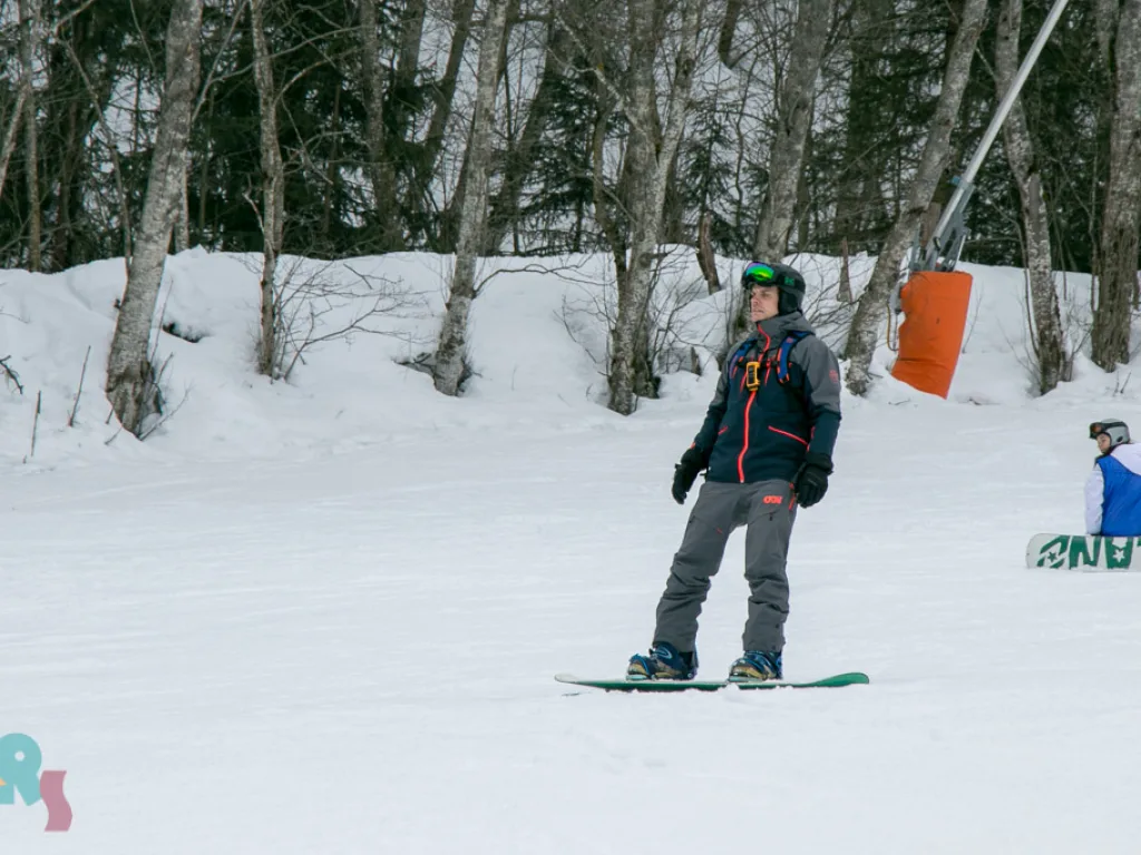 Snowboarder in dunkler Kleidung auf der Piste.